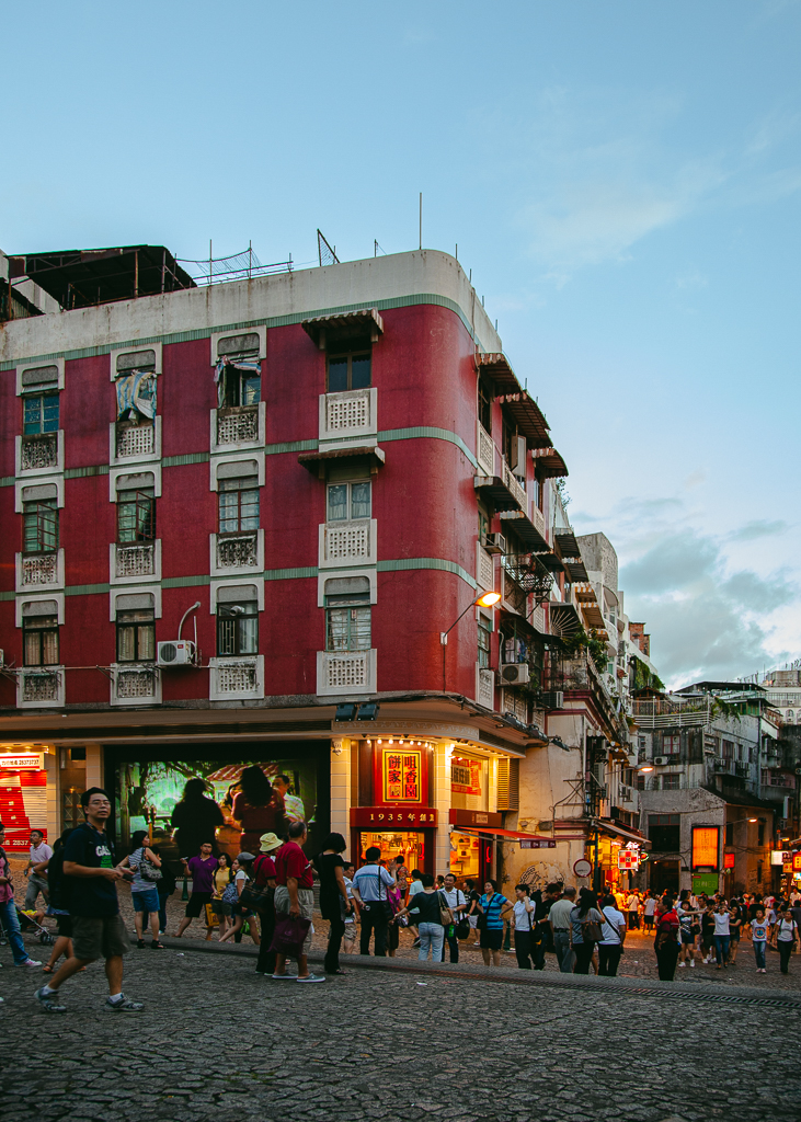 A busy intersectional street with a building pained in fainted red and white paint in Santo Antonio.